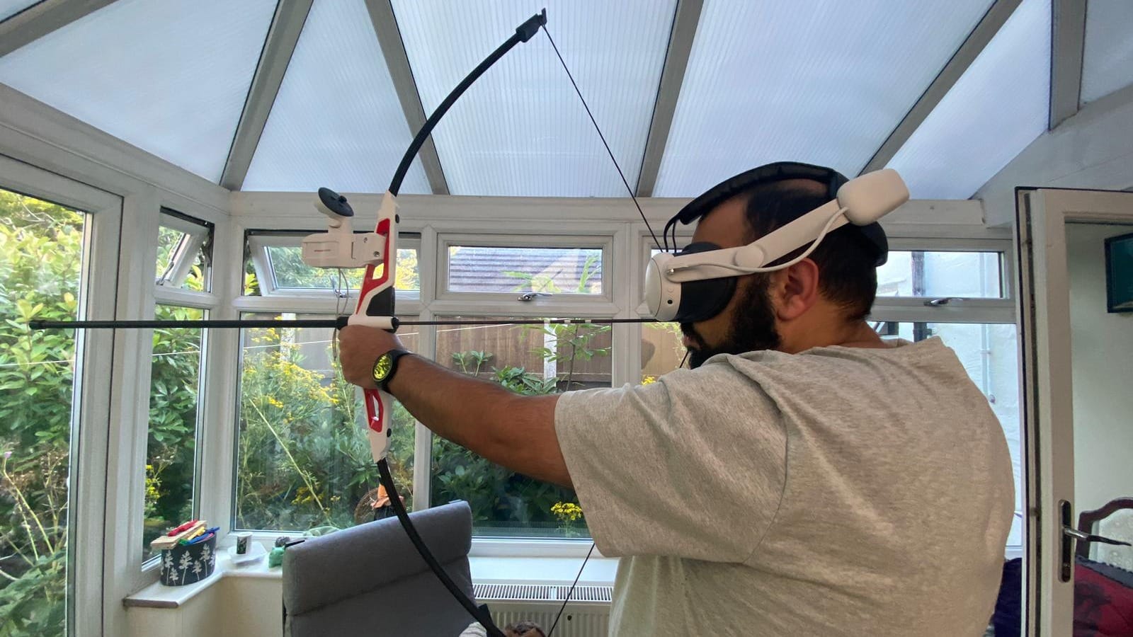 Man holding the Artemis bow indoors while wearing a Quest 3 headset