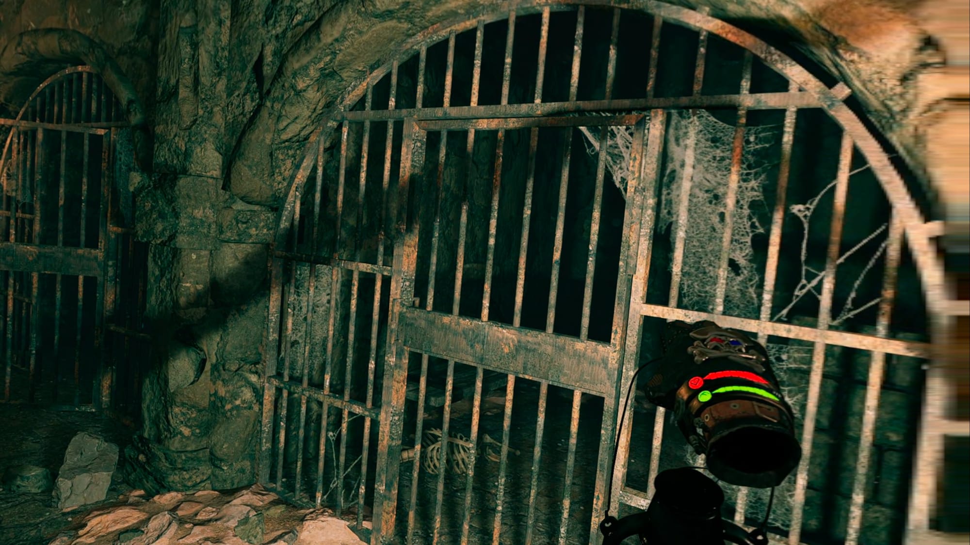 Someone holding a lit lantern near an abandoned prison cell with a skeleton inside