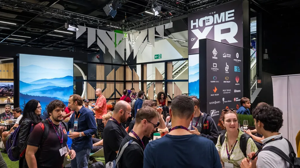 Large group of people talking while both sitting down and standing up around the "Home of XR" booth